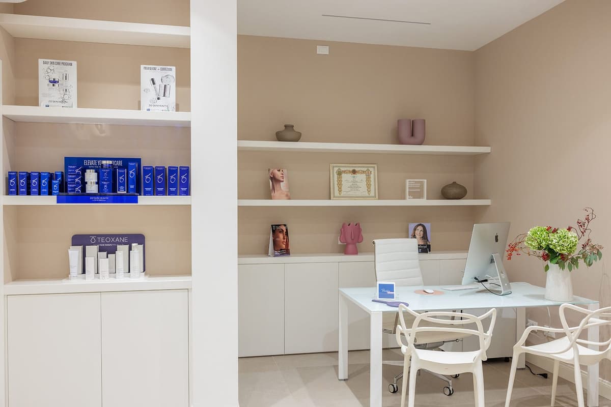 Stanza elegante di centro estetico, arredamento moderno, prodotti bellezza sugli scaffali, computer su scrivania bianca.